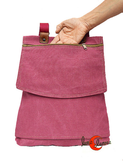 Mochila de tela plana con tapa. Tiene un bolsillo grande en la misma tapa.