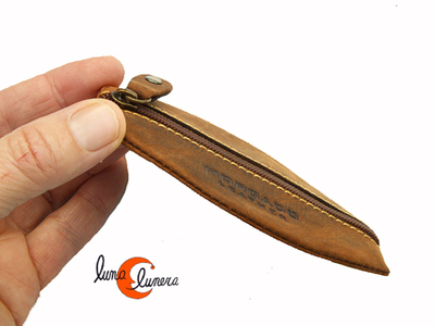 monedero de piel ovalado con una cremallera y aro para llaves.