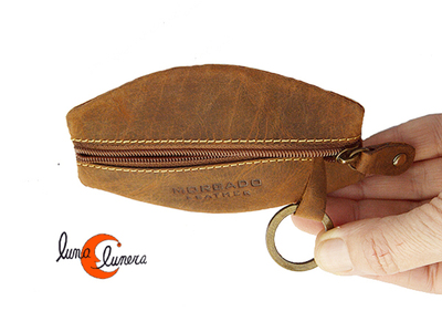 monedero de piel ovalado con una cremallera y aro para llaves.