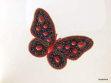 Colección Broches de Porcelana. Broche muy grande con forma de mariposa hecho con pedrería y piezas de porcelana, predominando el color rojo sobre negro.