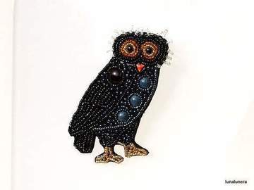 Colección Broches de Porcelana. Broche con forma de búho hecho con pedrería, con piezas de porcelana gris sobre fondo negro.