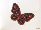 Colección Broches de Porcelana. Broche muy grande con forma de mariposa hecho con pedrería y piezas de porcelana, predominando el color rojo sobre negro.